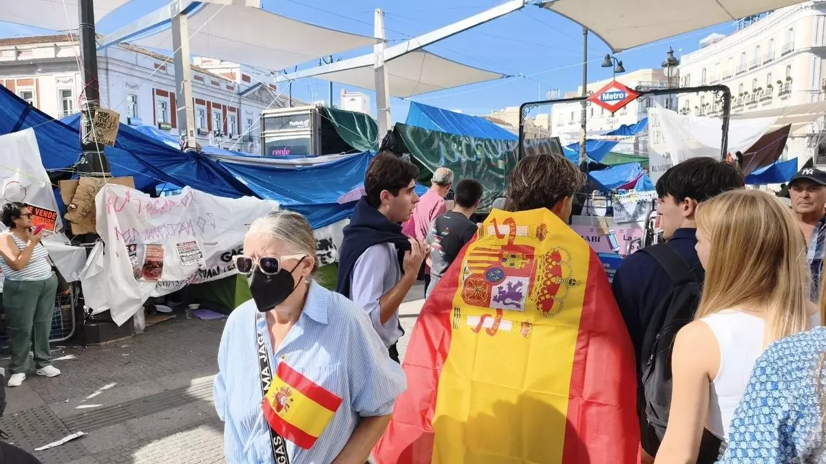 Varias personas con banderas de Espa&ntilde;a pasan por la Puerta del Sol.- Guillermo Mart&iacute;nez